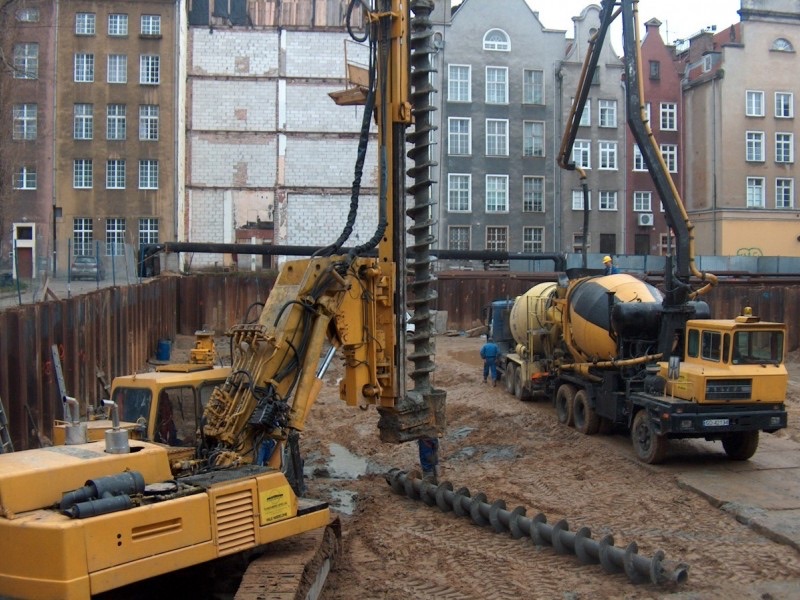 Wiertnica i betonowóz przy obudowie wykopu wśród kamienic Gdańska